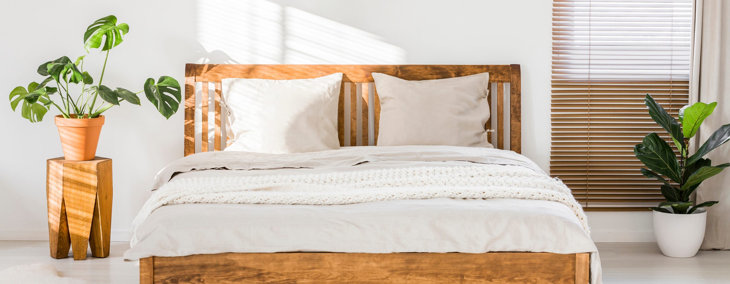 Close-up of double wooden bed with bedding, pillows and blanket